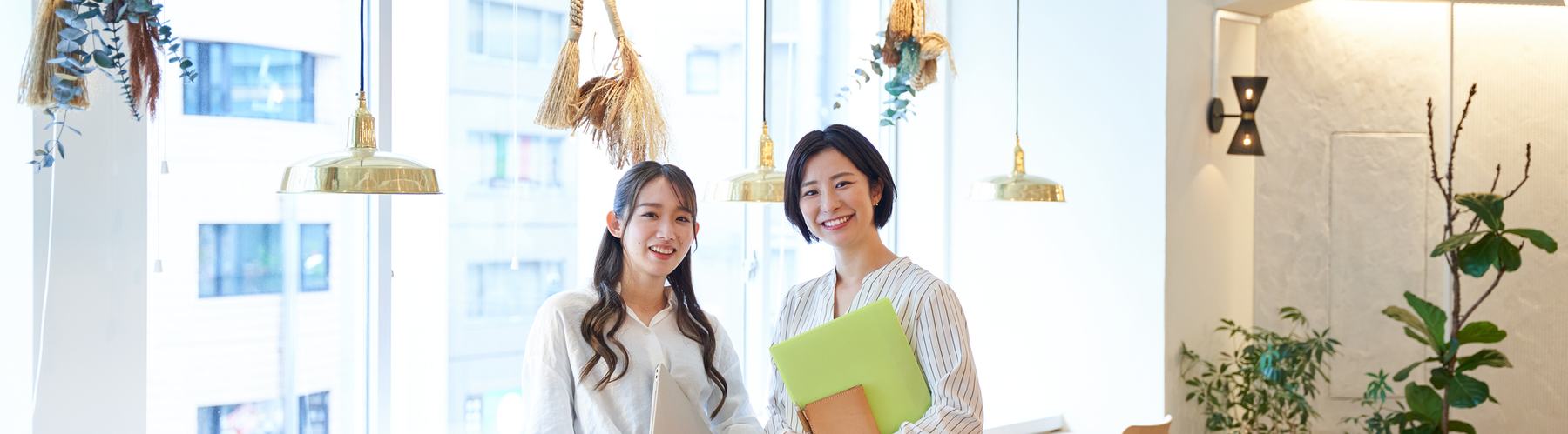 資料を手に、明るい表情で並んで立つ2人の担当者